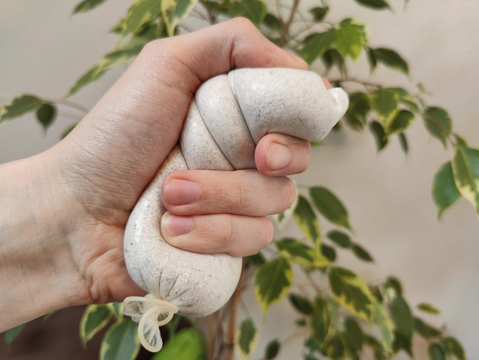 Et utgått kondom fylt med sand, i hånden på noen som bruker det som stressball.